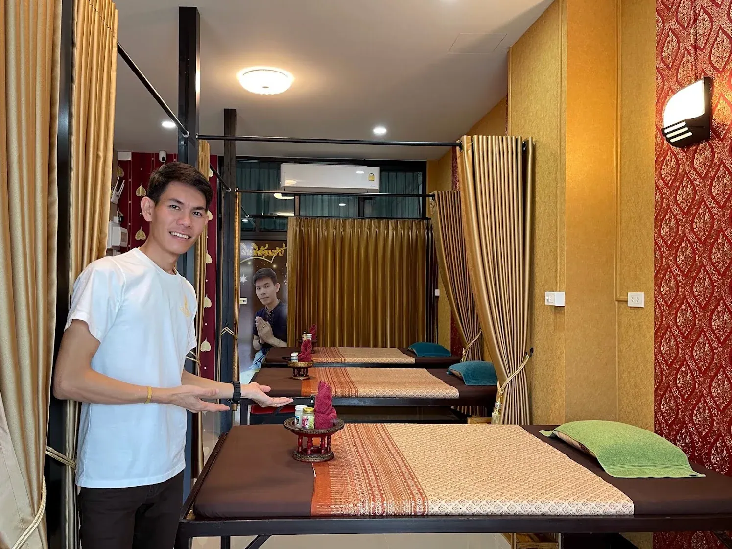 หมอแซมสวมเสื้อสีขาวยืนต้อนรับภายในร้านแซมนวดเพื่อสุขภาพ